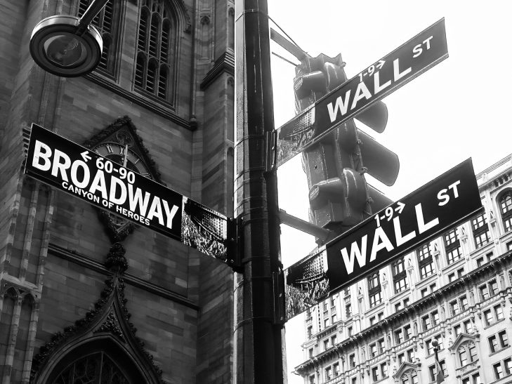 New York city boardwalk street sign giving directions to Wall St and Broadway