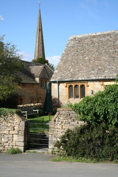 This image displays the slender spire of St. Michael and All Angels Church in Stanton, Gloucestershire