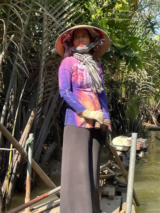 Vietnamese woman steering boat on Mekong River