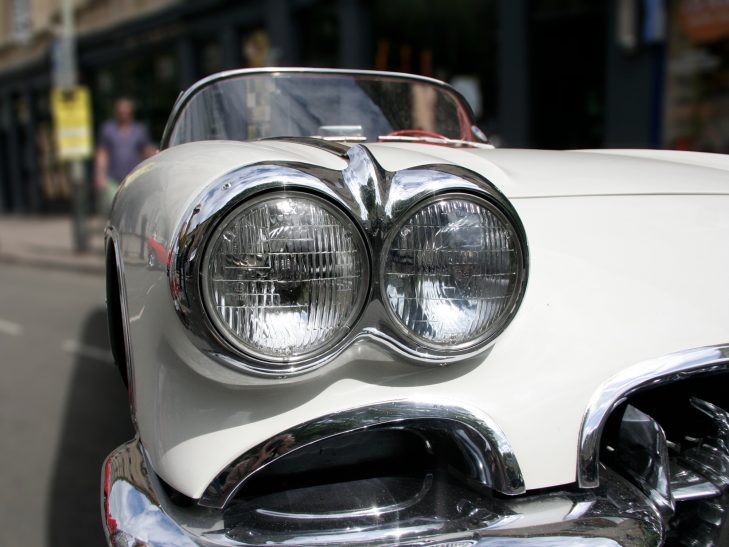 Image showing the dual headlights and chrome trim of a classic white Chevrolet Corvette C1,