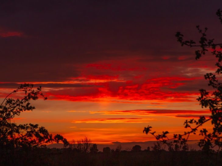 Deep red skyline where the setting sun reflects off a clouded sky