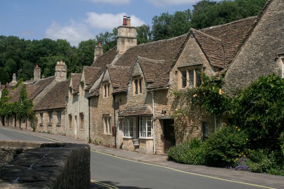 The image shows the historic stone cottages and bridge in Castle Combe, Wiltshire,